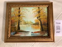 Framed small original oil painting illustrating a calm autumn landscape with trees by a river, signed by the artist at the bottom left corner.