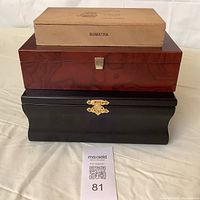 Stacked view of three wooden boxes showing front latches; Sumatra cigar box on top, reddish-brown wood box middle, and black Crown Royal box bottom.