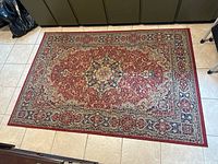 Top-down view of rectangular area rug on tile floor showing full pattern and colors in natural light.