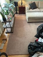 Living room view showing large light brown rug under sectional sofa and coffee table.