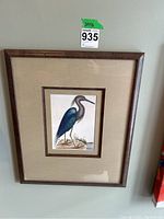 Full view of the framed heron print hanging on a wall showing frame and matting.