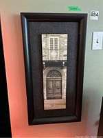 Full view of first framed print showing sepia-toned architectural details including wooden door and shuttered window with iron balcony.
