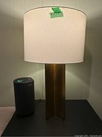 First lamp in pair on table with fabric shade illuminated, showing metal base and shade shape.