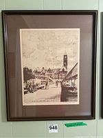 Framed limited edition black and white cityscape print in dark wood frame hung on a wall with visible label 948 below.