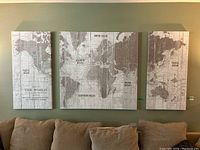 Group shot of three stretched canvas world map prints over sofa