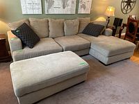 Front view of entire sectional sofa with ottoman and throw cushions