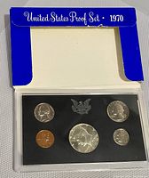1970 US S Proof Coin Set in blue cardboard holder, plastic case visible with five coins inside.