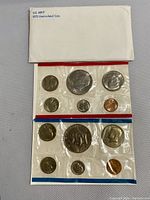 Photo of two uncirculated 1975 US Mint Bicentennial coin sets in red and blue bordered sealed cellophane packaging with coins visible including dime, quarter, half dollar, penny, and silver dollar.