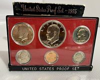Front view of the 1975 US Bicentennial proof coin set in plastic case with red lining and original packaging showing wear, lid separated.