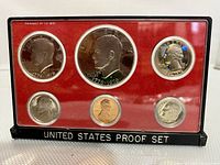 Front view of 1976 US S Proof Bicentennial Coin Set in plastic case showing six coins with red background and clear plastic cover.