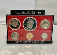 Front view of 1978 US Proof Coin Set in plastic case with six proof coins visible, red insert and black base, casing showing wear.