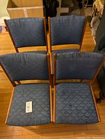 Top view showing four blue upholstered dining chairs with teak wood frames.