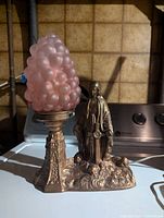Full item showing bronze figurine beside pink glass bubble shade on bronze pedestal