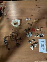 Photo showing assortment of earrings, Lucite rose bracelet, hoop and bangle bracelets on wooden surface