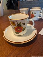 Close-up of a cup and saucer from the lot showing California Poppies floral design and brown rim detail