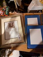 Photo showing three picture frames: one large ornate frame and two smaller blue mat frames