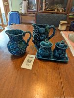 Two ceramic pitchers and jam/jelly set on wooden table with label