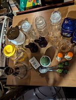 Top-down view of all glass jars, ceramic jars, Pyrex jug and decorative items arranged on a wooden table.
