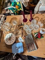 Photo of the lot showing glassware, red bud vases, creamer, clock, spoons, salt and pepper shakers
