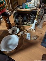 Photo showing the vintage framed clock with mother of pearl inlay, multiple trinket dishes, a brown vase with floral art, white ceramic vase, and small mother of pearl animal figurines on a wooden table