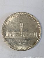 Front side of the 1939 Canada silver dollar coin showing Parliament buildings and inscriptions.