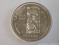 Clear top-down image showing entire front face of the 1958 Canada silver dollar coin highlighting the totem pole design and inscriptions.