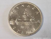 Full view of the 1959 Canada silver dollar coin reverse side showing two men paddling a canoe with tree background and year 1959