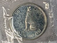 Reverse of the 1967 Canadian silver centennial half dollar coin showing a seated howling wolf and centennial date inscriptions.