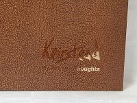 Close-up of book cover with brown textured surface and partially visible gold embossed text 'Keirstead thoughts'.