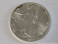 Obverse of the 1990 silver dollar coin showing Lady Liberty with sun rising, showing the date and inscriptions.
