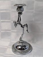 Full view of the silver-tone figurine candle holder showing the female figure balancing on one leg with the candle holder on the raised arm.