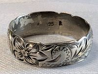 Close-up of carved sterling silver ring band showing floral and leaf motif along with '925 A' silver marking inside the band.