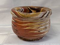 Side view of indigenous pottery vessel showing variegated earthy colors and thick irregular rim