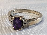 Close-up view of sterling silver ring with purple amethyst and floral metalwork on sides.