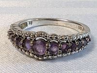 Front view showing five purple cabochon amethyst stones in graduated row with milgrain border.