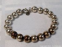 Full view of sterling silver ball bracelet on white fabric showing the whole piece including clasp.