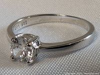 Close-up front angled view of sterling silver ring with clear stone showing the 925 mark inside the band.