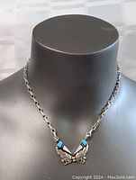 Full view of silver chain necklace with butterfly pendant on display bust.