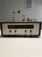 Front view showing wood veneer casing, aluminum front panel, gold-tone knobs