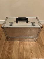 Closed vintage Mac Cosmetics metal makeup train case with hammered silver finish, black handle, and two latches.