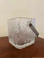 Front angle view of the square textured glass ice bucket with visible stainless steel handle attached on side.