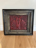 Frontal image of framed vintage terracotta red peacock art, showing detailed textured surface and rustic wood frame.