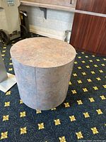 Round coffee table with faux stone marble-like top and cylindrical body; muted grey and brown tones.