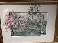 Framed watercolor painting showing pink blossoming trees, pond with swan boats, and Boston city buildings