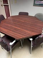 Photo of octagonal lunch table with wood look surface and four chairs around it.