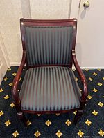 Front view of one wooden waiting room chair showing the upholstered seat and back with vertical stripes, and curved armrests.