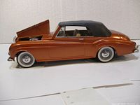 Side view of metallic bronze 1961 Bentley die-cast model car with hood open, showing length and exterior details.