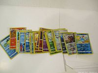 Front view showing an array of assorted Pokémon cards with various types including grass, water, and fire types, as well as trainer and energy cards.