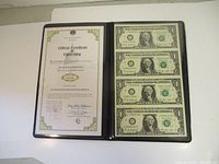 Protective folder with certificate of ownership on left side and four uncut $1 bills on right side.