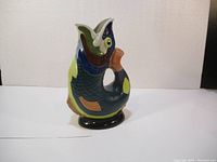 Front and side view of a colorful dartmouth pottery jug vase shaped and decorated as a stylized fish with vibrant colors and detailed glaze work.